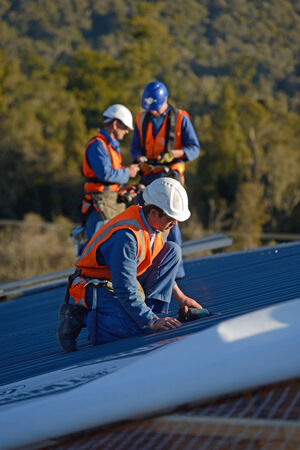 GREYMOUTH, NEW ZEALAND, SEPTEMBER 6, 2014: A team of contractors put the roof on a large commercial building near Greymouth, New Zealand, September 6, 2014のeditorial素材