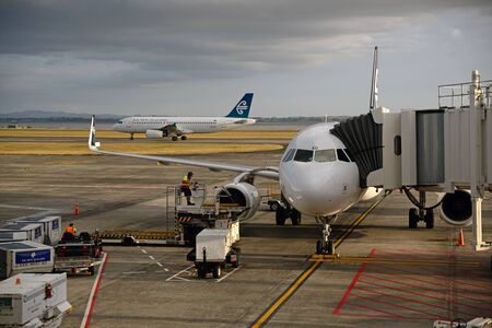 An Air New Zealand jet lands at Auckland Airport while another takes on passengers, Northland, New...