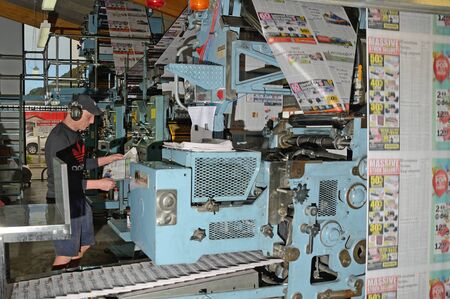 GREYMOUTH, NEW ZEALAND, MAY 22, 2015:  An unidentified printer checks the quality of his workmanship while printing a newspaper on May 22, 2015 in Greymouth, New Zealand.のeditorial素材