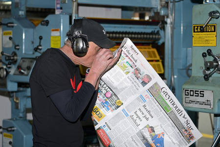 GREYMOUTH, NEW ZEALAND, MAY 22, 2015:  An unidentified printer checks the quality of his workmanship while printing a newspaper on May 22, 2015 in Greymouth, New Zealand.のeditorial素材