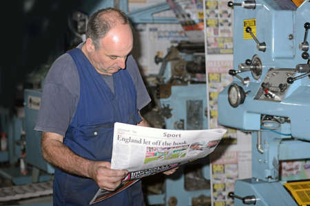 GREYMOUTH, NEW ZEALAND, MAY 22, 2015:  An unidentified printer checks the quality of his workmanship while printing a newspaper on May 22, 2015 in Greymouth, New Zealand.のeditorial素材