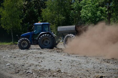 A tractor spreads blood and bone fertiliser on a paddock in Westland, New Zealandの写真素材