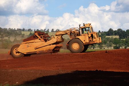 MEMERAMBI, AUSTRALIA, MARCH 31, 2016: A caterpillar 623B paddle scraper at work on a farm featuring rich red volcanic soil near Memerambi, Queensland, Australia on 31.3.2016. These machines are commonly used in road construction and mining operations.のeditorial素材