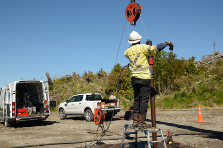 MOANA, NEW ZEALAND, OCTOBER 27, 2017: An oil well engineer directs a crane operator to position a pulley for the wireline during an operation to log the condition of steel casing inside an abandoned oil well.のeditorial素材