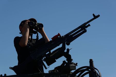 GREYMOUTH, NEW ZEALAND, NOVEMBER 18, 2017: An unidentified schoolboy scans the horizon with binoculars at an open day run by the New Zealand armed forces. The machine gun is a Mag 58 GM.のeditorial素材