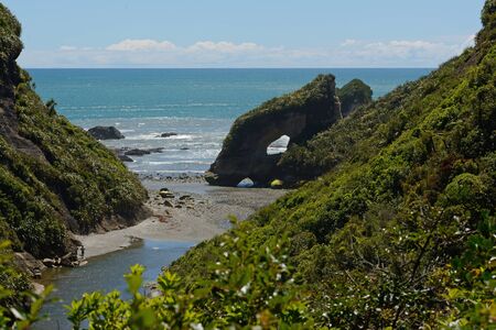 native bush frames a beach at low tide on a West Coast beach, South Island, New Zealandの写真素材