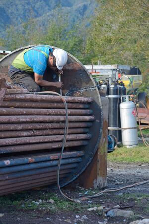 GREYMOUTH, NEW ZEALAND, MAY 14, 2018: An unidentified engineer cuts up an old boiler for scrap metal