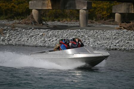 TARAMAKAU RIVER, WEST COAST, NEW ZEALAND, SEPTEMBER 3, 2019: Three young men power their jetboat down the Taramakau Riverのeditorial素材