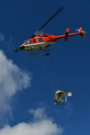 GREYMOUTH, NEW ZEALAND, SEPTEMBER 2 2021: A helicopter carries a monsoon bucket while spreading...
