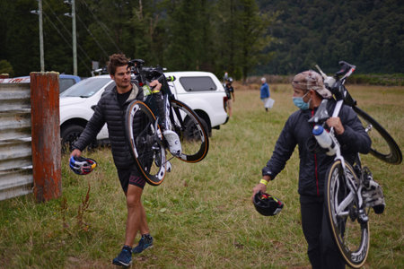 AICKENS, NEW ZEALAND, FEBRUARY 12, 2022; A support team member, left, carries the bicycle for Braden Currie, the winner of the male elite section of the Coast to Coast Triathlonのeditorial素材