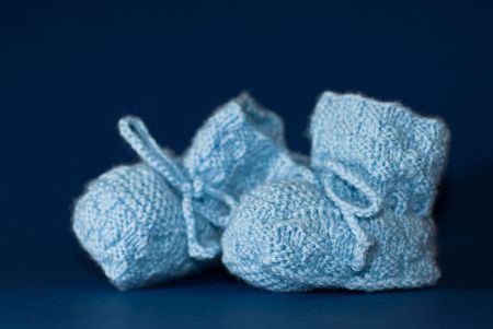 Two blue baby shoes on dark blue background (shallow dof)