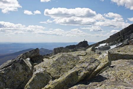 Young man is standing at the top of the rock looking ahead.の写真素材