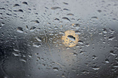 Rain drops at window with orange  brigth spot.
