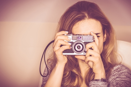 Vintage Camera Photography. Young Woman in Her 20s Taking Pictures Using Aged Vintage Photo Camera.の写真素材