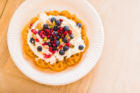 Plate of waffles with fresh blueberries, pomegranate and whipped creamの写真素材