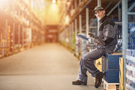 Warehouse Supervisor Job. Caucasian Worker Making Documentation in the Storage Facility.の写真素材