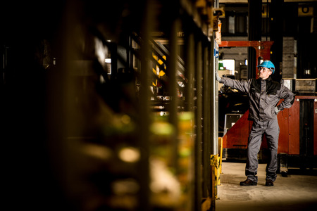 Caucasian Warehouse worker with blue Safety Helmet. Dark colors.の写真素材