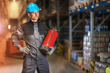 Caucasian warehouse worker with fire extinguisher. Safety concept.の写真素材