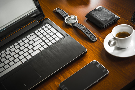 Laptop computer, coffe, watch, glasses and wallet on wooden deskの写真素材