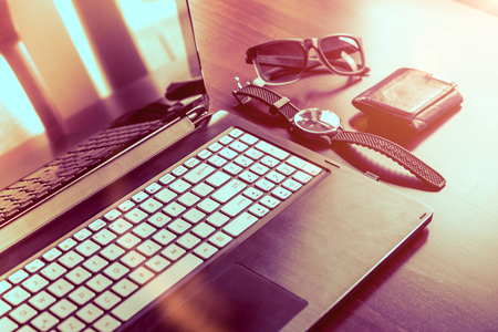 Laptop computer, watch, glasses and wallet on wooden table.の写真素材