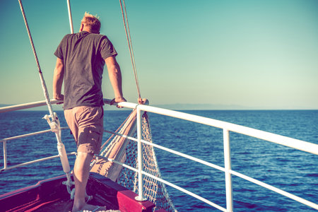 Caucasian Middle Aged Man Standing at the Bow of the Boat Enjoying His Vacation by the Sea. Sunny...