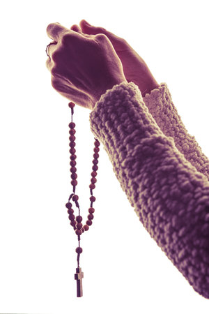 Woman Hands Raising Catholic Wooden Rosary to Pray. Isolated on White Background. Prayer concept.の写真素材