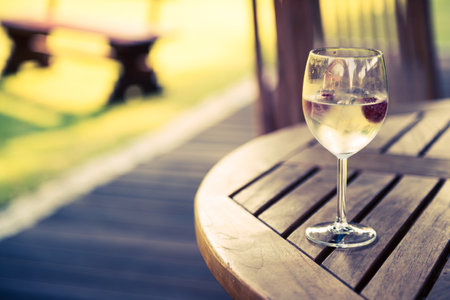 Closeup of Glass of Chilled Champagne with Frozen Raspberries Inside Standing on a Table in the Backyard Garden. Holiday Rest Outside the City. Vacation Theme.の写真素材