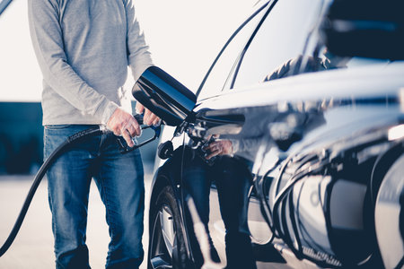 Caucasian Man Refuels His Modern Car at Gas Station Wearing Disposable Gloves to Follow Safety Rules. transportation Theme.の写真素材