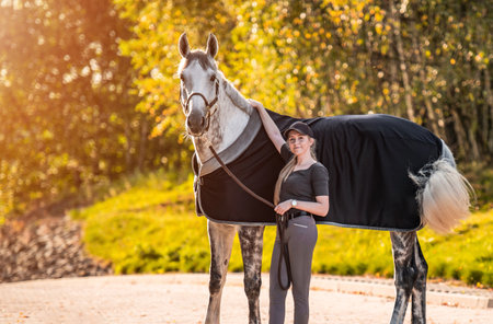Young horse rider girl standing with her horse. Equestrian theme.の写真素材