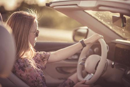 A young girl behind the wheel of a convertible. Summer vibes. happy woman.