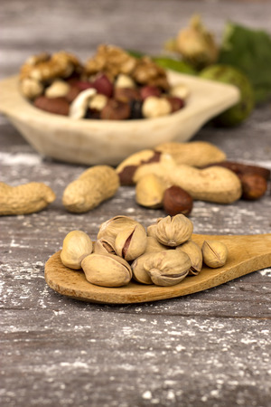 assorted nuts in a wooden bowl on a rustic surfaceの写真素材