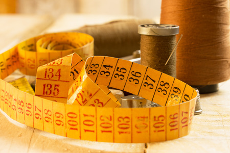 sewing tools: tape measure,boobbins on a wooden surfaceの写真素材
