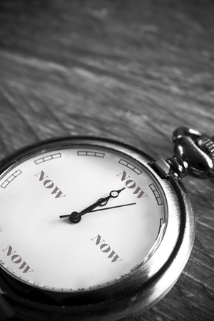 pocket watch on a vintage table showing the time "now"の写真素材