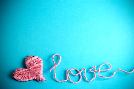 pink clews in shape of heart and text love over a blue backgroundの写真素材