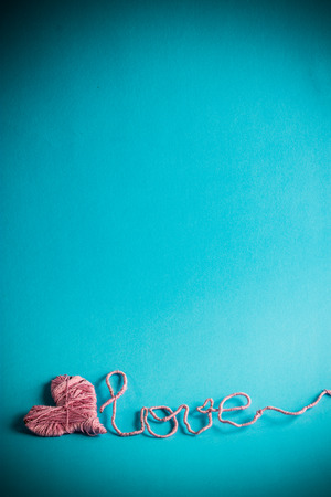 pink clews in shape of heart and text love over a blue backgroundの写真素材