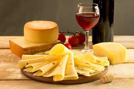 assorted cheese with red wine on a rustic tableの写真素材