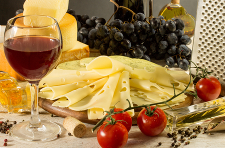 variety of cheese and red wine on a rustic tableの写真素材