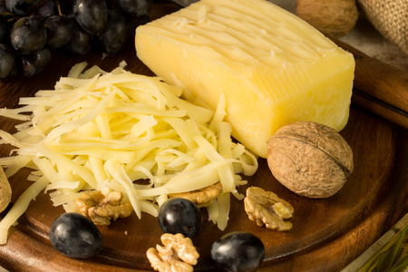 cheese on a cutting board with grape and nutsの写真素材