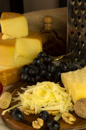 cheese on a cutting board together with grape and nutsの写真素材
