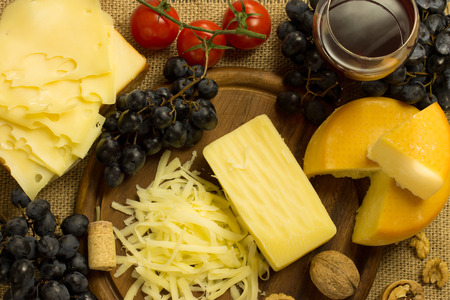 various cheese with grape,wine and nuts on a cutting boardの写真素材