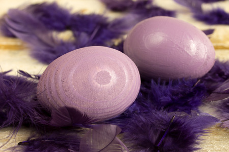 purple easter eggs with feathers on old wooden tableの写真素材