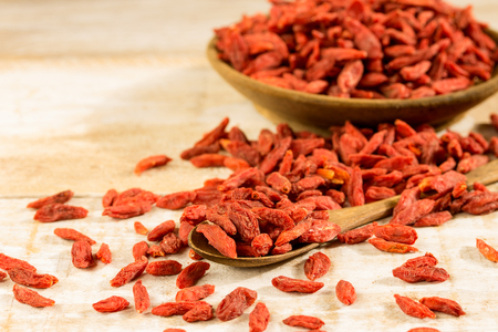 Wooden bowl and spoon with goji berries on a vintage table closeupの写真素材