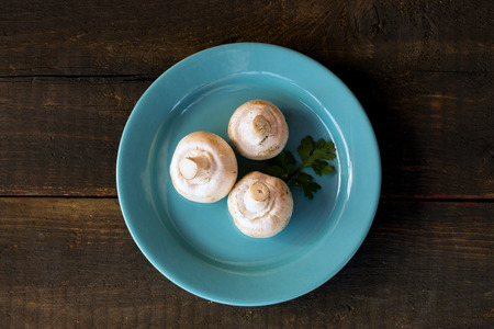 mushrooms on a blue plate ckgroundover wooden baの写真素材