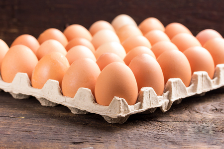 Chicken eggs in the package on a wooden tableの写真素材