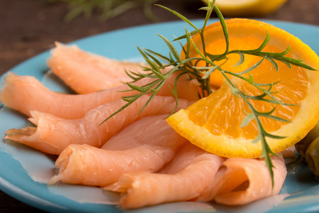 raw smoked salmon with dill and orange on a blue plateの写真素材