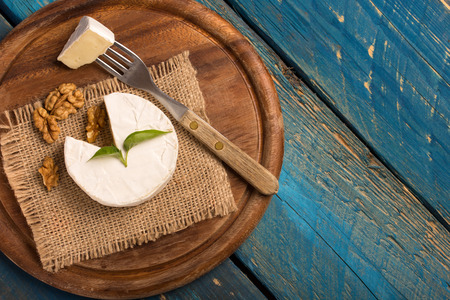 camembert cheese on a cutting board over a blue wooden tableの写真素材