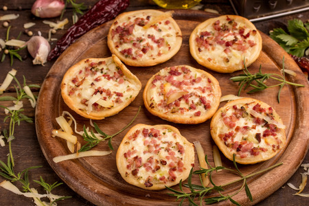 mini pizzas and food ingredients on a cutting boardの写真素材