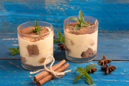 two glass of tiramisu dessert on a blue tableの写真素材