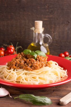 Italian spaghetti with a meat based bolognese, or bolognaise, sauce on a red plateの写真素材