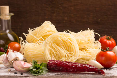 pasta nests with food ingredients over dark wooden backgroundの写真素材